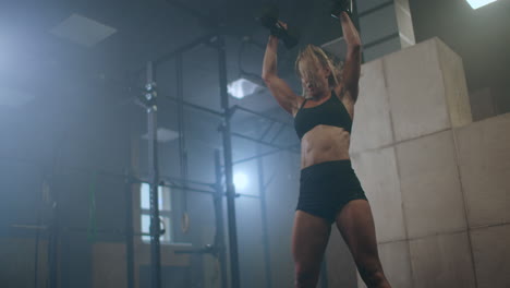 A-woman-raises-dumbbells-over-her-head-during-a-workout.-Weight-lifting.-Heavy-training-in-the-gym.